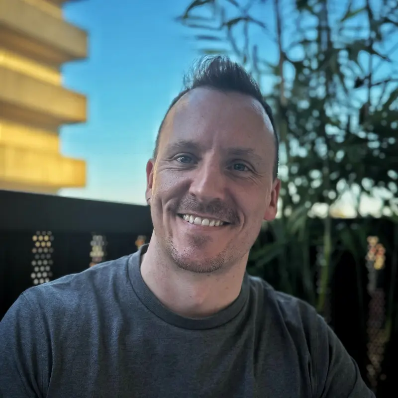 A coach smiling at the camera outdoors